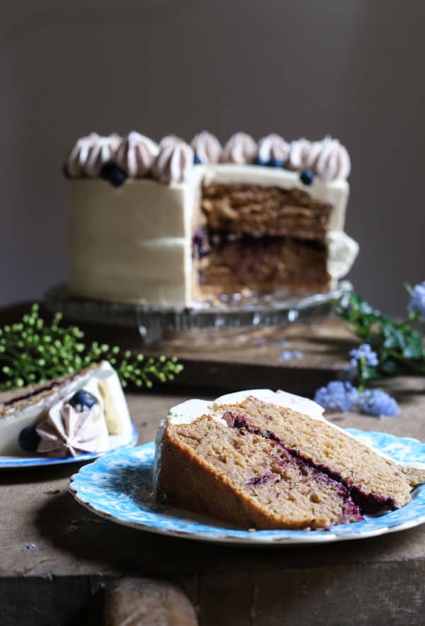 A slice of Apple Blueberry Maple Cake on a plate in front of the cake