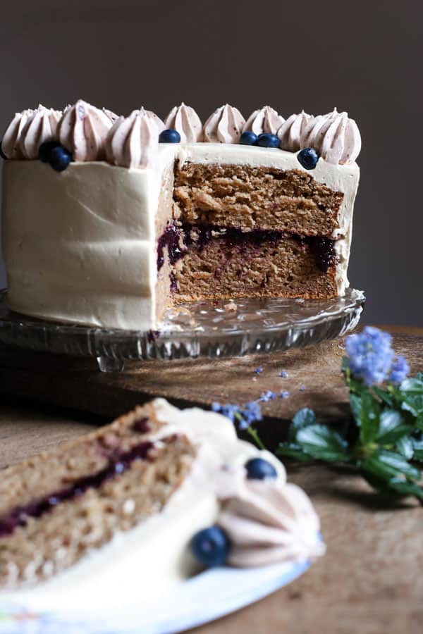 A slice of Apple Blueberry Maple Cake on a plate in front of the cake