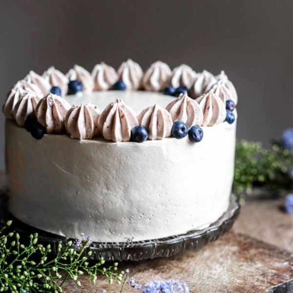 Apple Blueberry Maple Cake on a wooden board surrounded by flowers