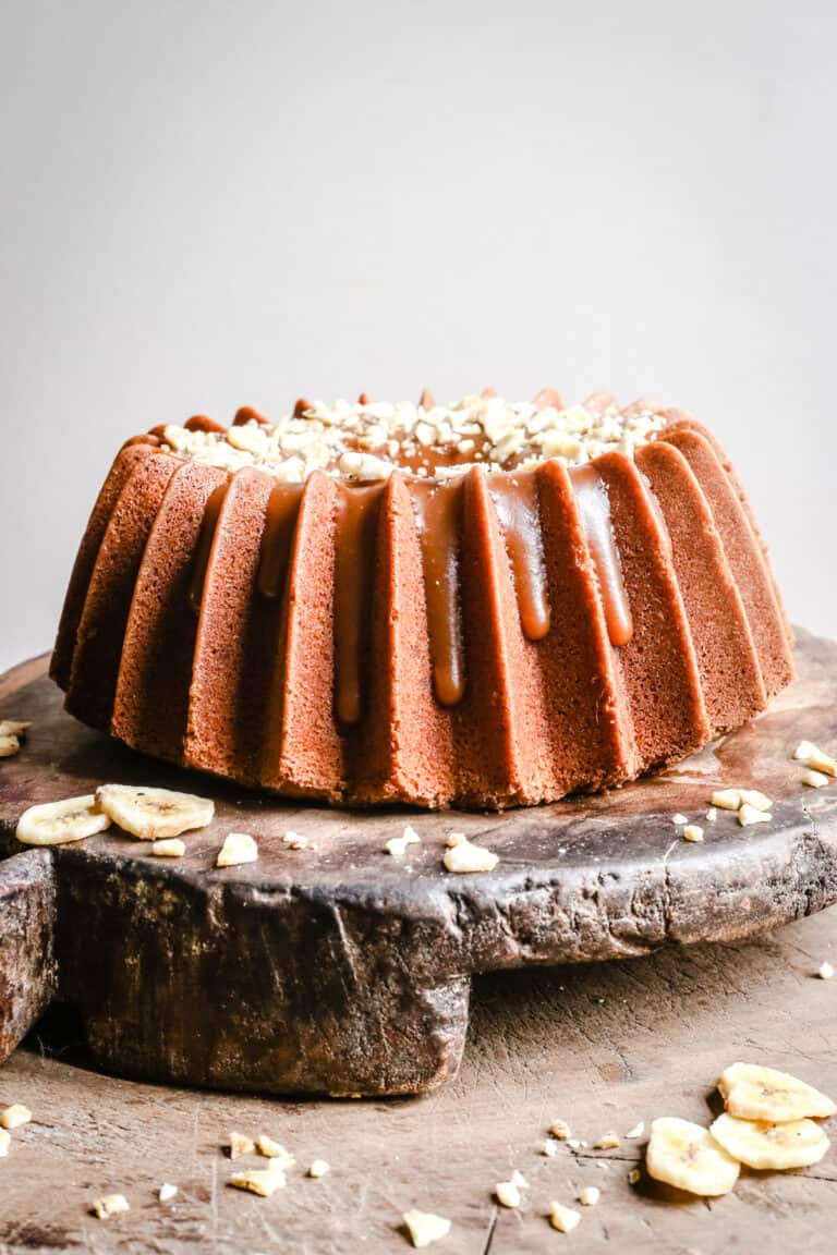 Banana Rum Caramel Cake on a wooden board surrounded by banana chips