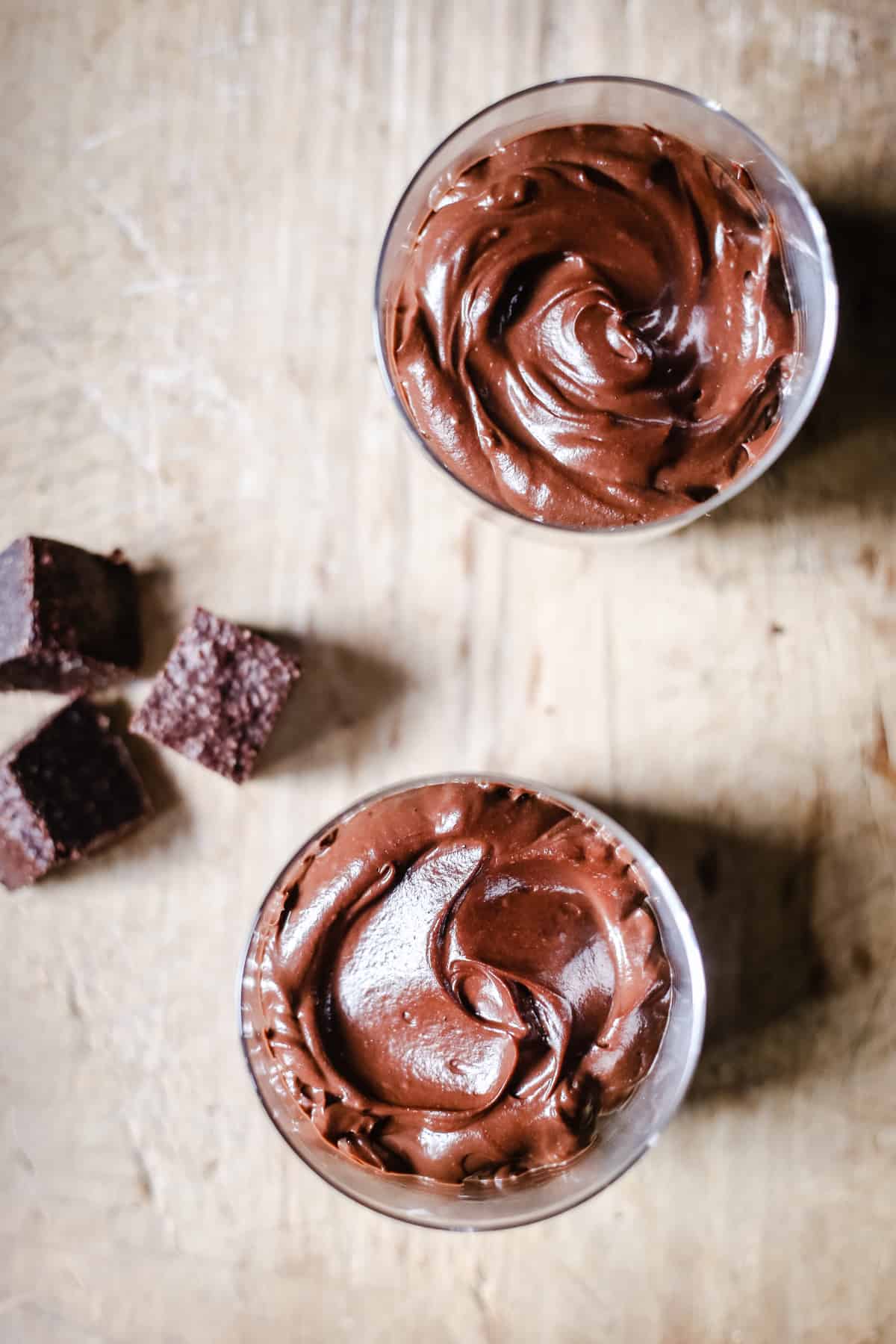 Chocolate Mousse in glasses on a wooden board surrounded by brownies pieces