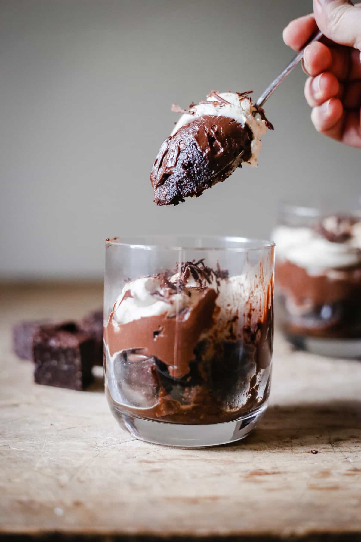 hand pulling a spoon out of a pot of Chocolate Brownie Trifle.