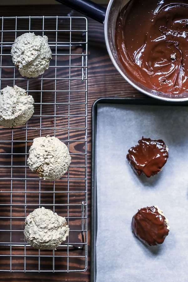 Coconut Matcha Macaroons being dipped into melted chocolate