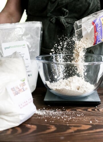 baker weighing flour in a glass mixing bowl