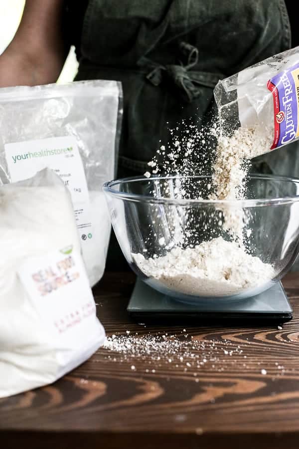 baker weighing flour in a glass mixing bowl