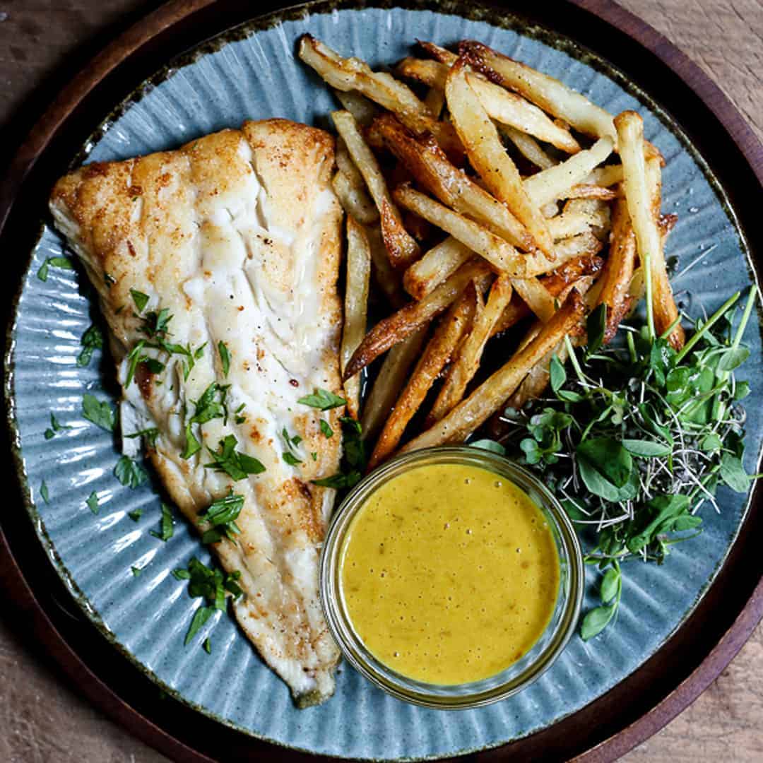 A plate of fish and chips with curry sauce