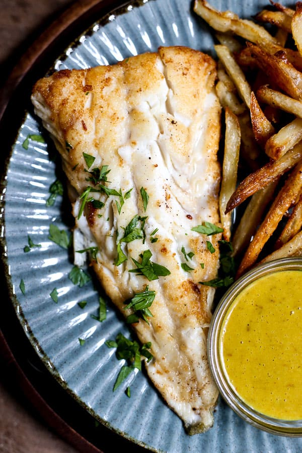 A plate of fish and chips with curry sauce