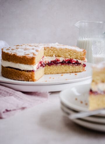 victoria sponge on a plate with slice taken out next to slice on a plate