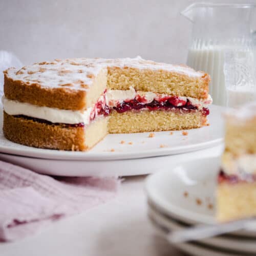 victoria sponge on a plate with slice taken out next to slice on a plate