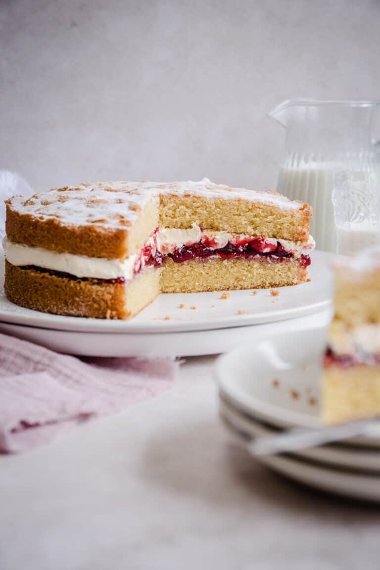 victoria sponge on a plate with slice taken out next to slice on a plate