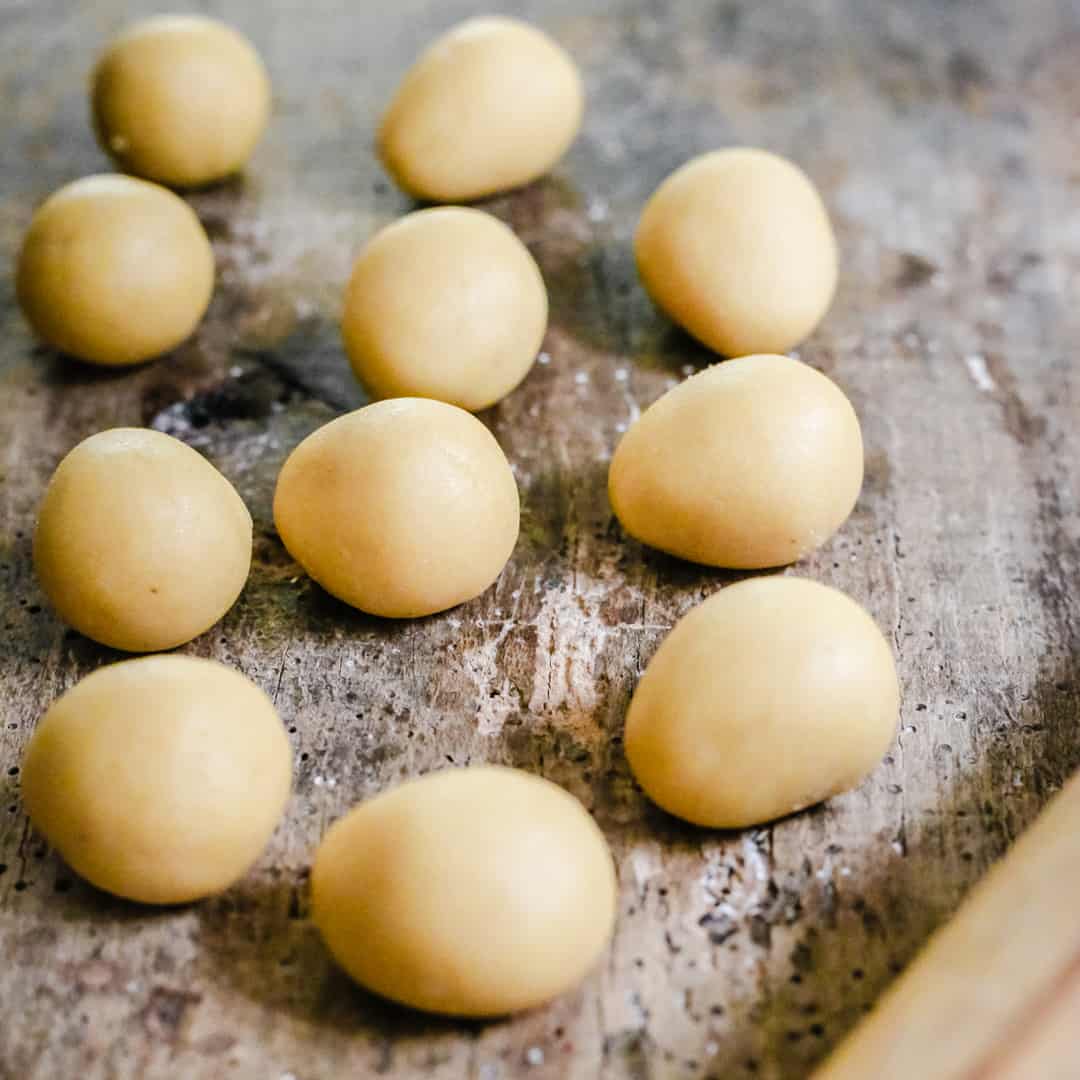 homemade marzipan dough rolled into balls on a wooden board