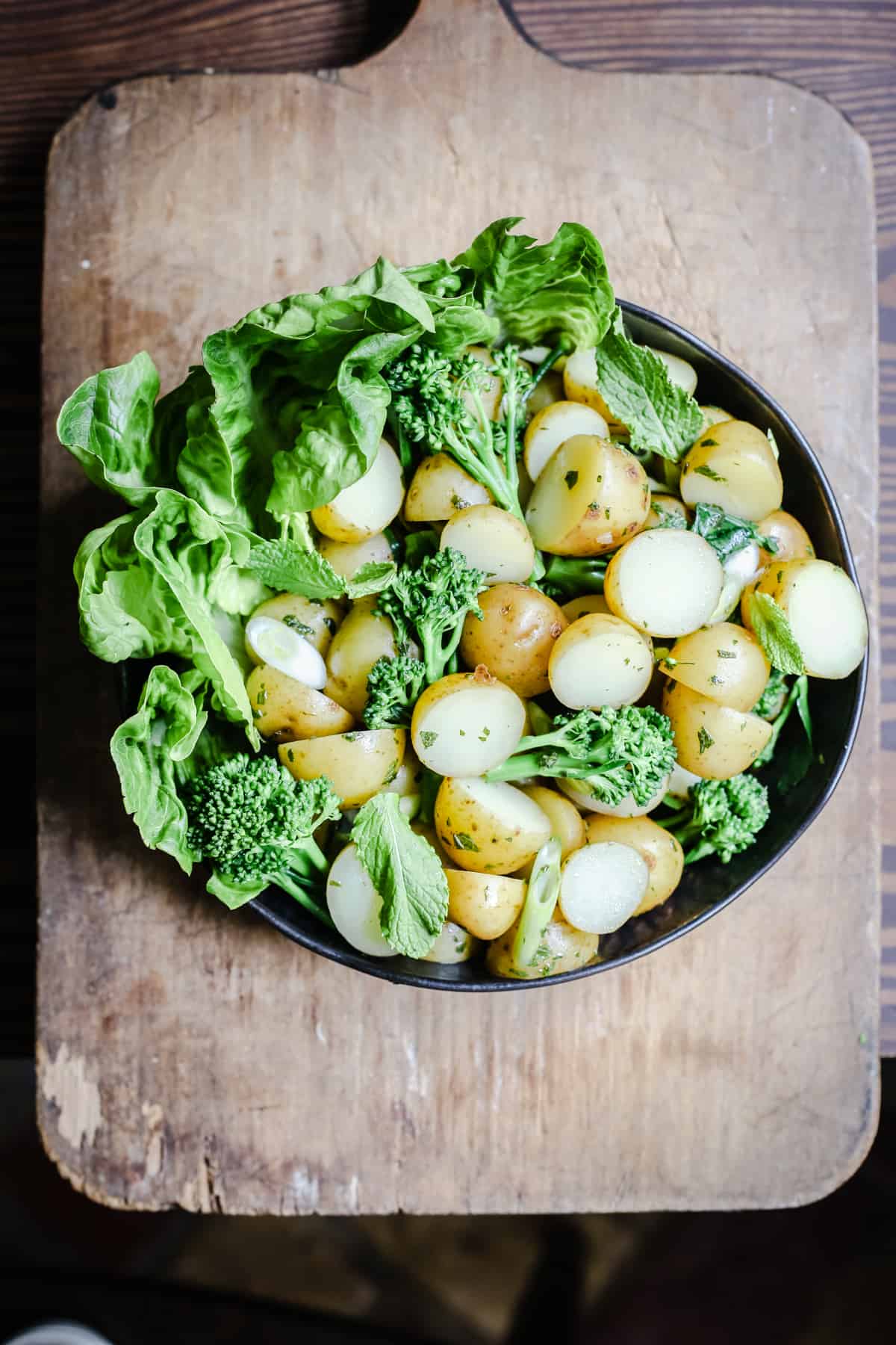 overhead view of a bowl of English Mint Potato Salad on a wooden board