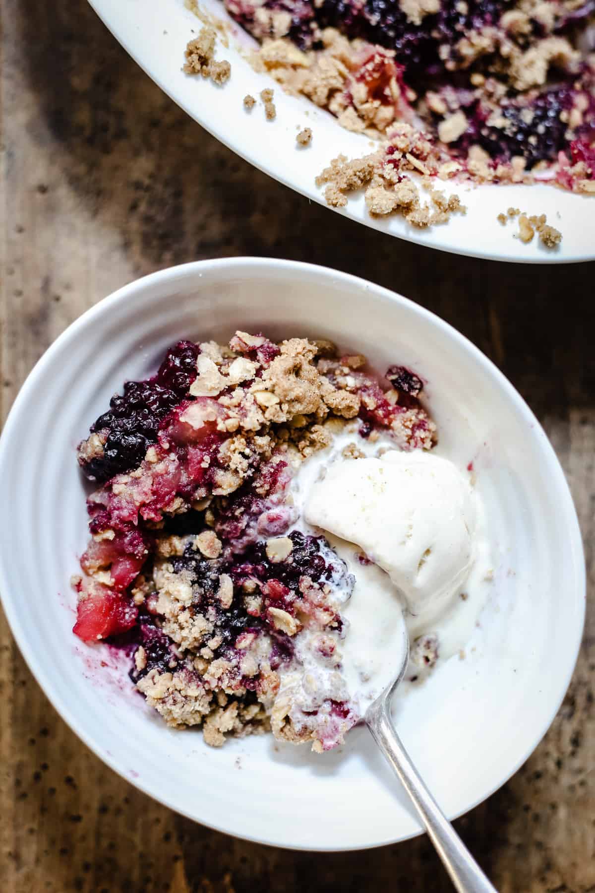 A bowl of apple and blackberry crumble with ice cream on top