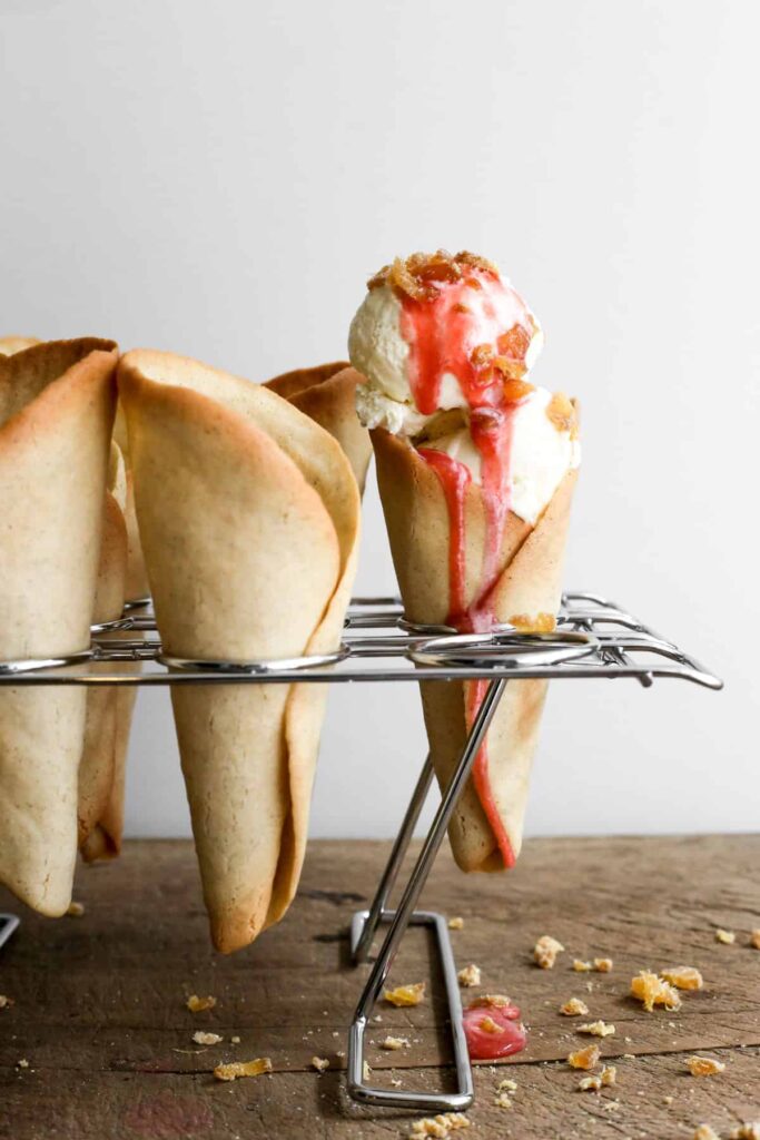 Ice cream cones in a stand, one filled with ice cream and sauce