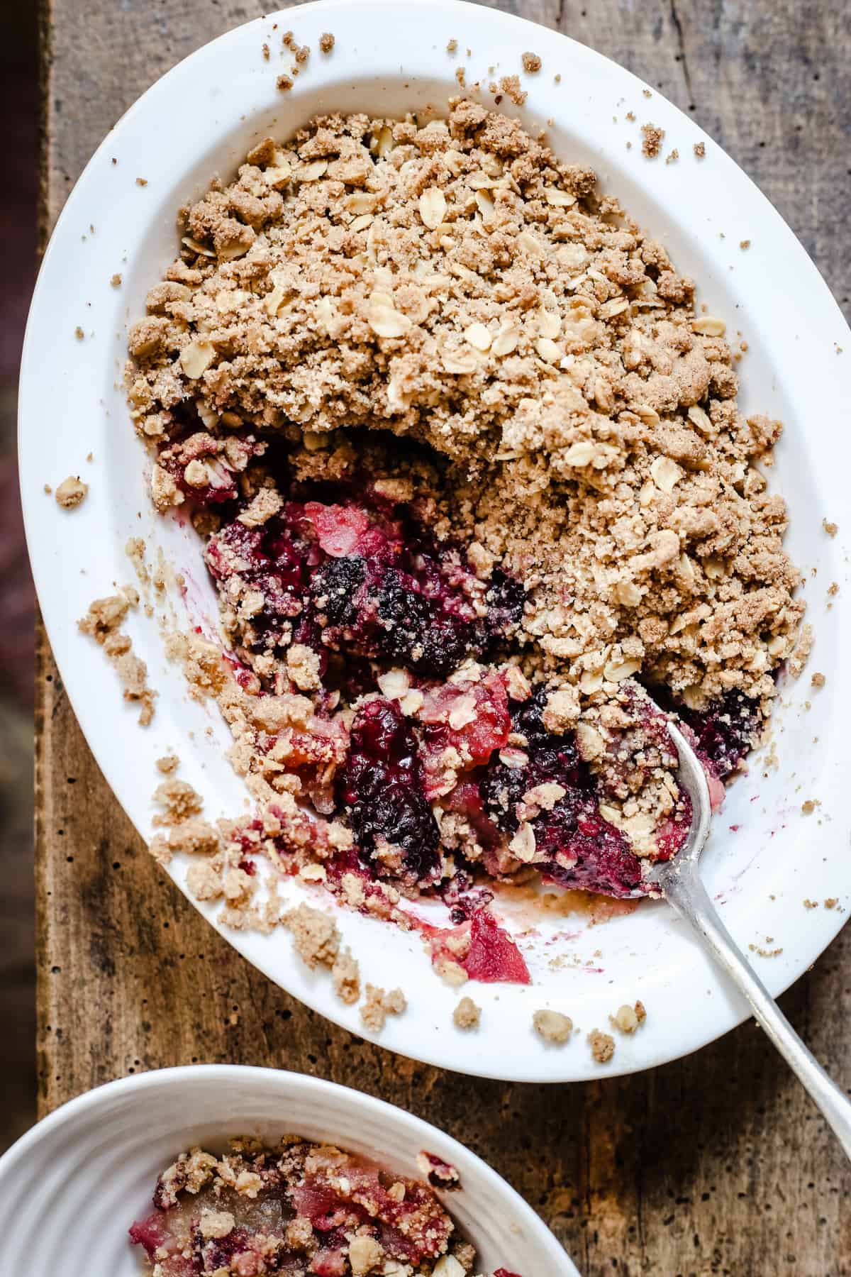 A dish of Apple and Blackberry Crumble with a portion taken out