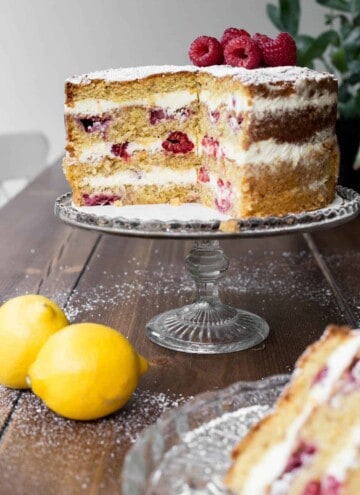 Cut Lemon Raspberry Cake on a cake stand with a slice in front