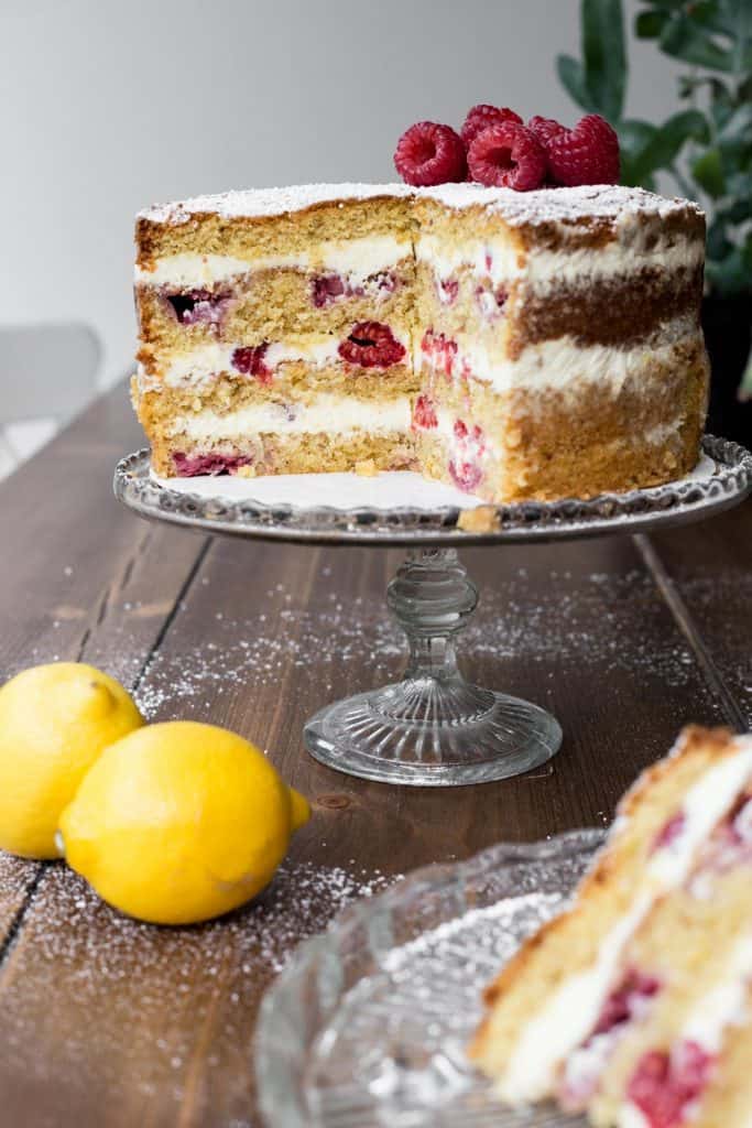 Cut Lemon Raspberry Cake on a cake stand with a slice in front