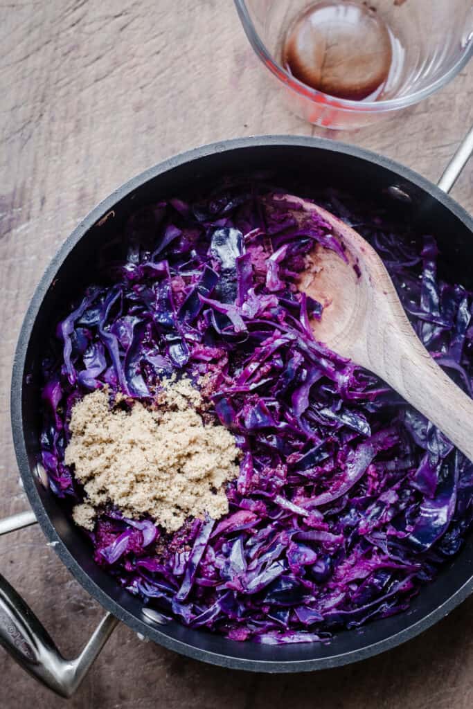 Process shot of making braised red cabbage in a large pan