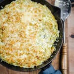 Cheesy & Creamy Brussels Sprouts Gratin in a cast iron pan on wooden board