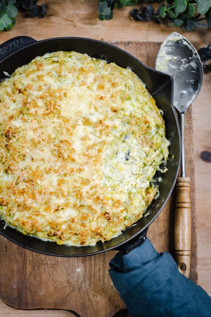Brussel Sprout and Leek Gratin in a cast iron pan on wooden board