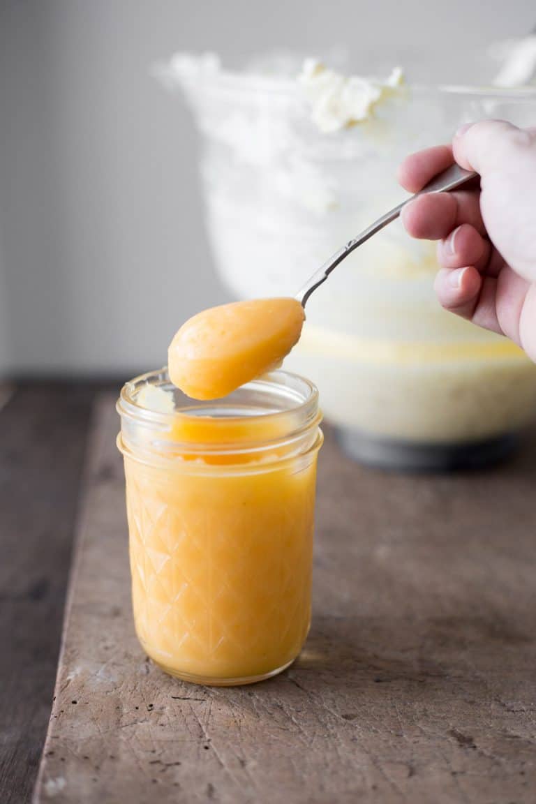 hand holding a spoon dipped into lemon curd