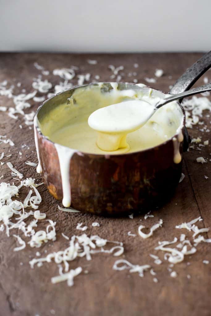 Gluten-Free Cheese Sauce in a saucepan on a wooden board