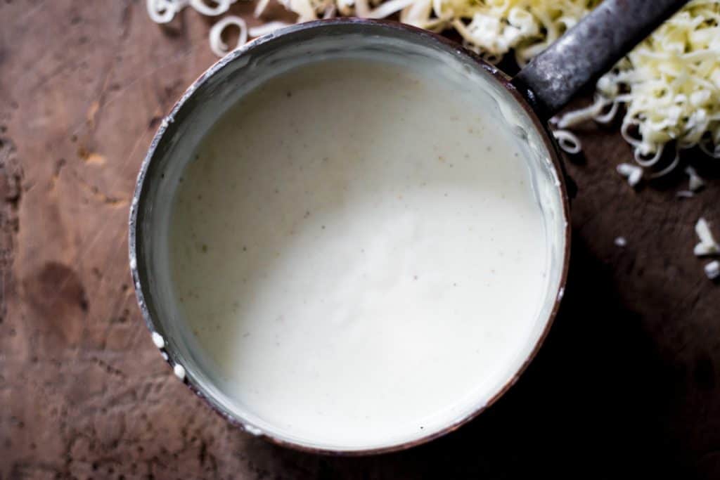 Gluten-Free Cheese Sauce in a saucepan on a wooden board