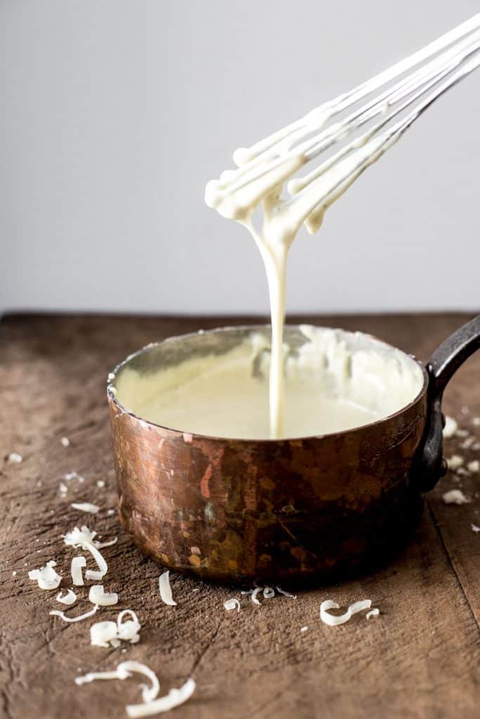 Gluten-Free Cheese Sauce in a saucepan on a wooden board