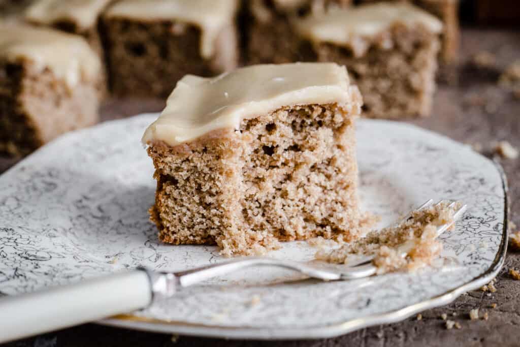 A slice of gluten-free caramel cake on a plate with a bite taken out of it