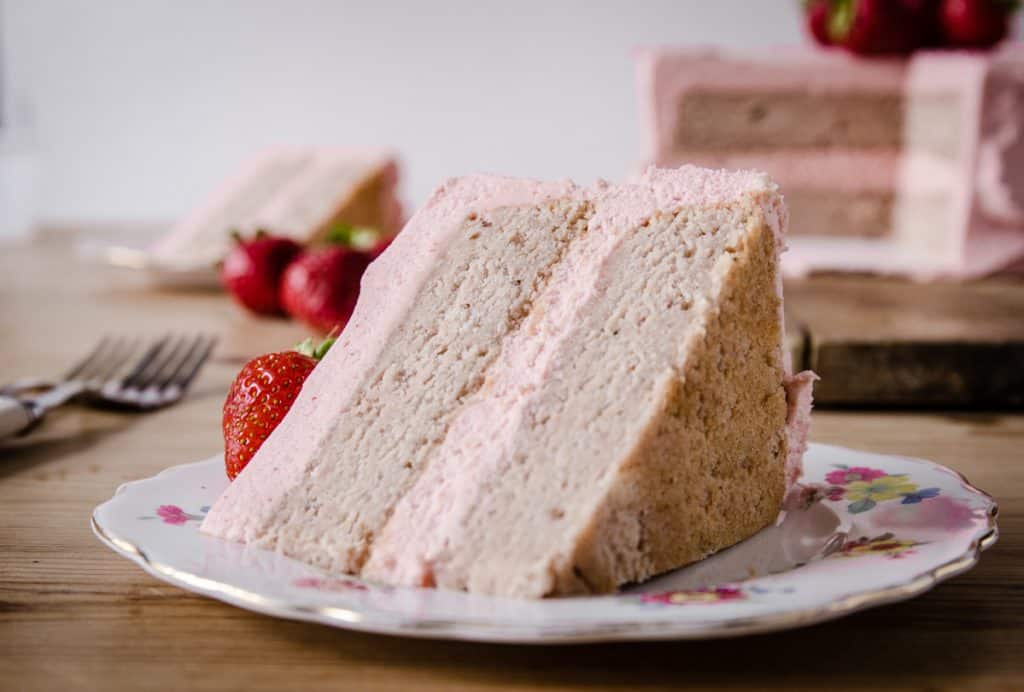 close up slice of strawberry cake on wooden board