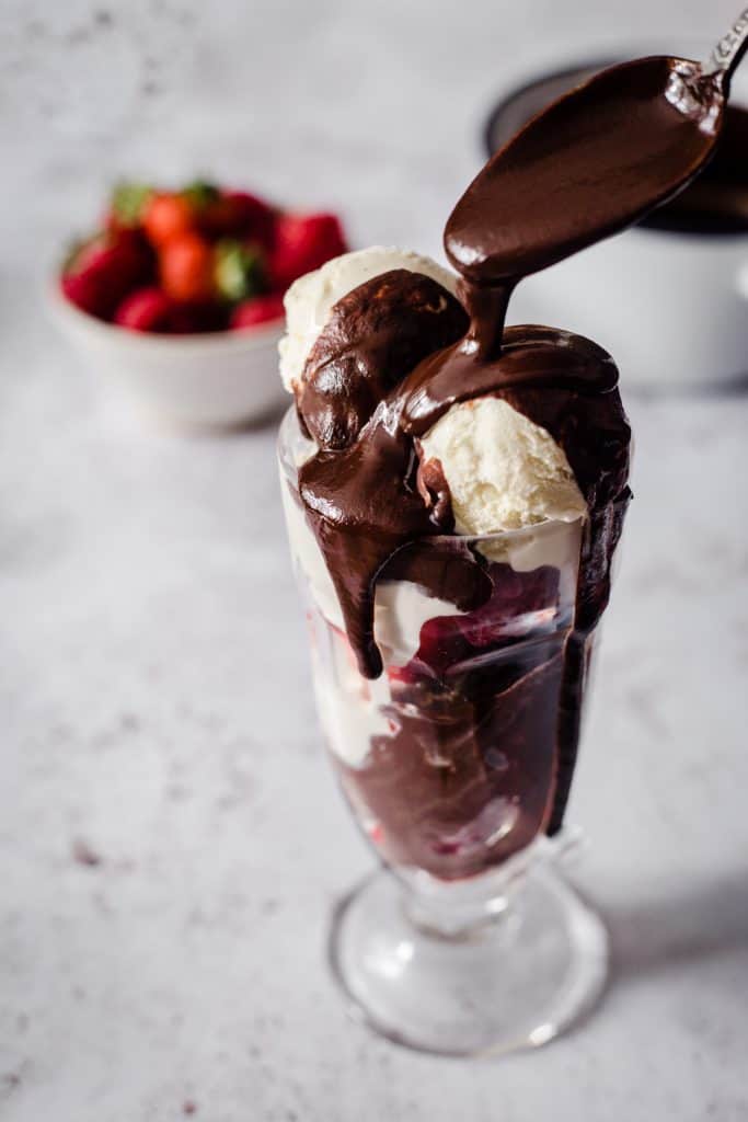 Ice Cream in a sundae glass with hot chocolate sauce being dripped over the top