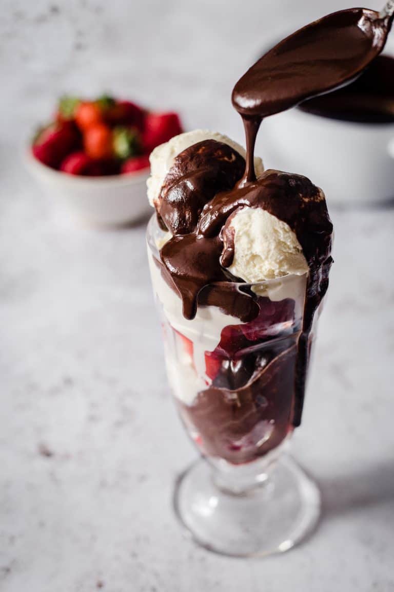 Ice Cream in a sundae glass with hot chocolate sauce being dripped over the top