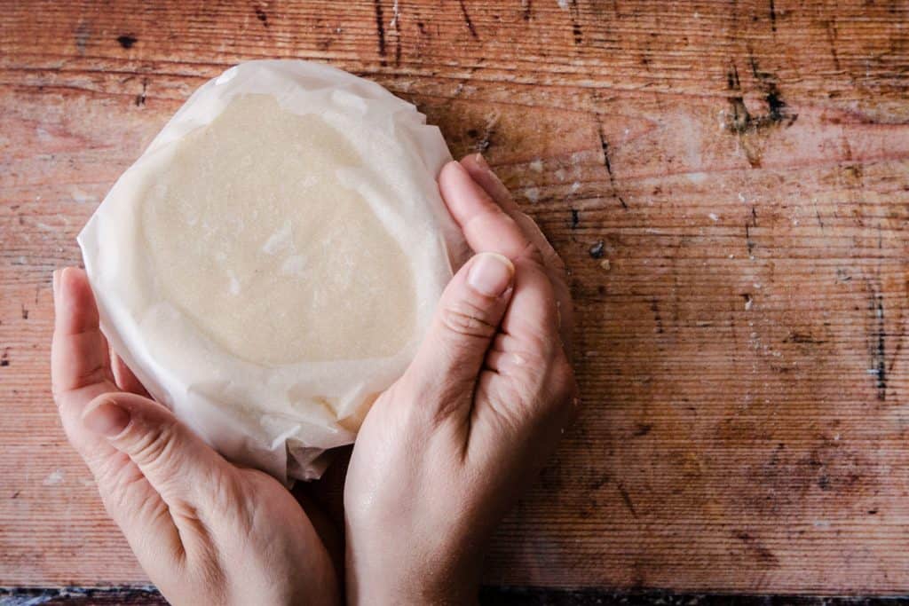 hands holding gluten free pastry wrapped in parchment paper