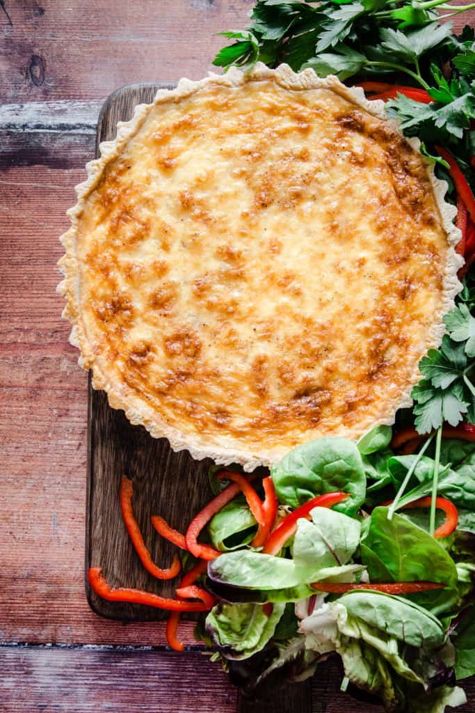 gluten-free quiche on a wooden board surrounded by salad