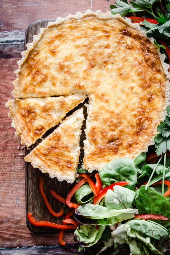 gluten-free quiche on a wooden board surrounded by salad