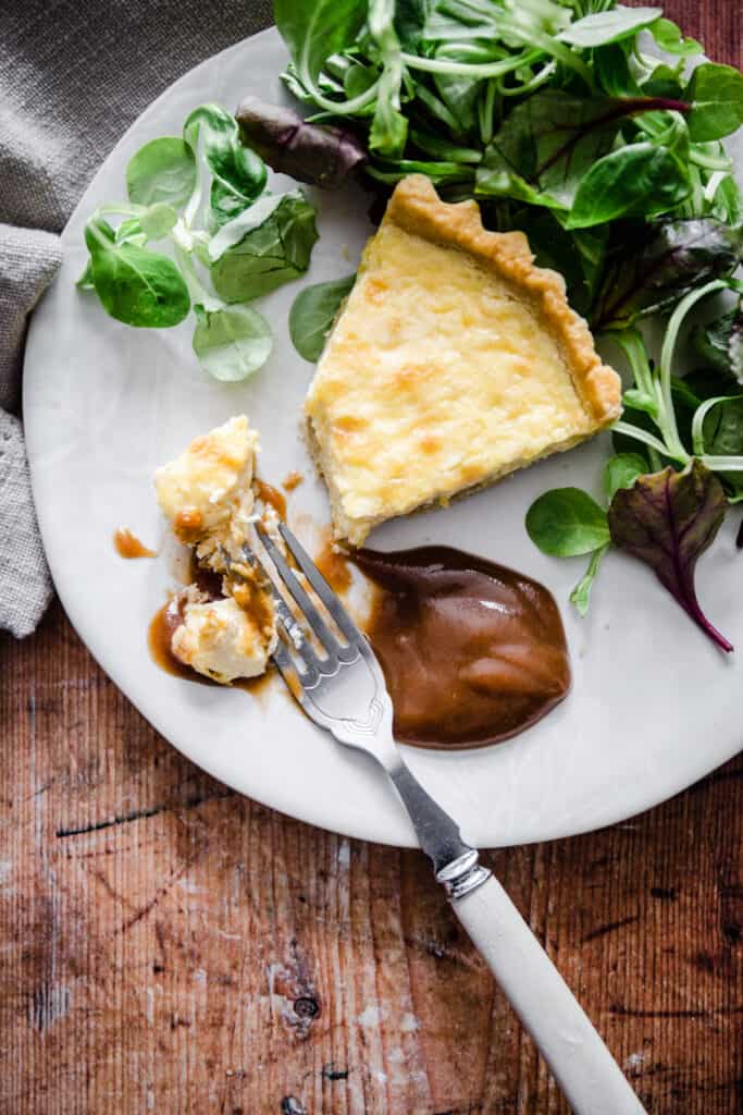 plate of brown sauce with quiche and a fork taking a bite.