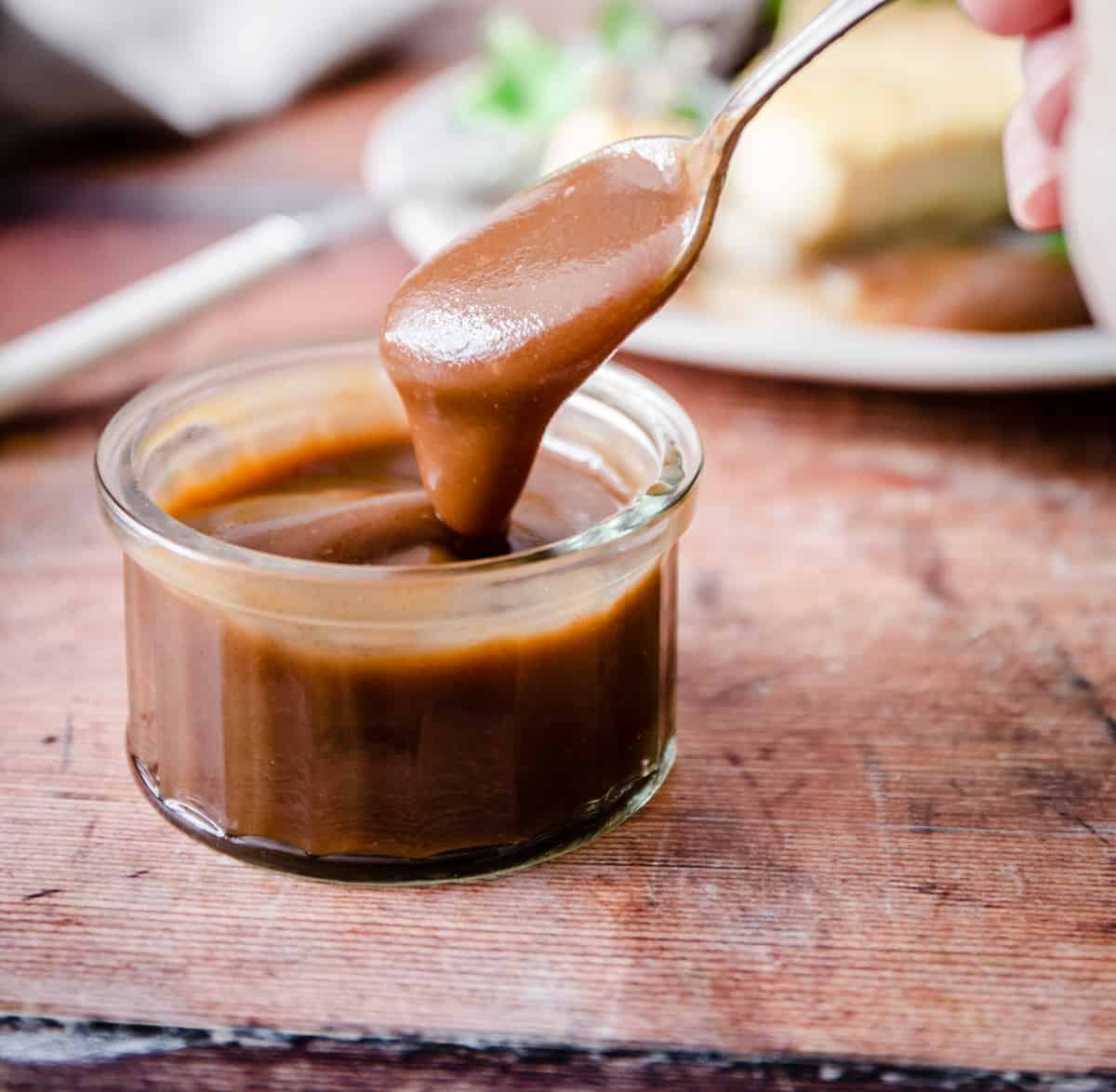 spooning out brown sauce from a glass dish