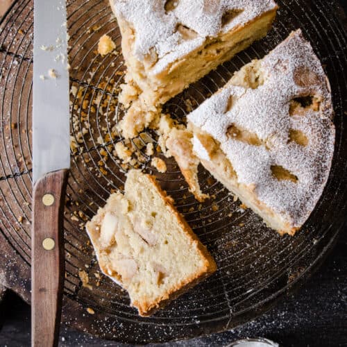 cut apple cake on a cooling rack next to a knife