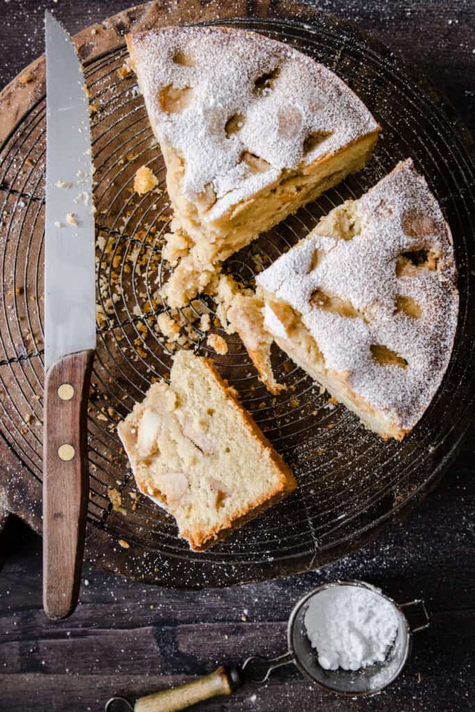 cut apple cake on a cooling rack next to a knife