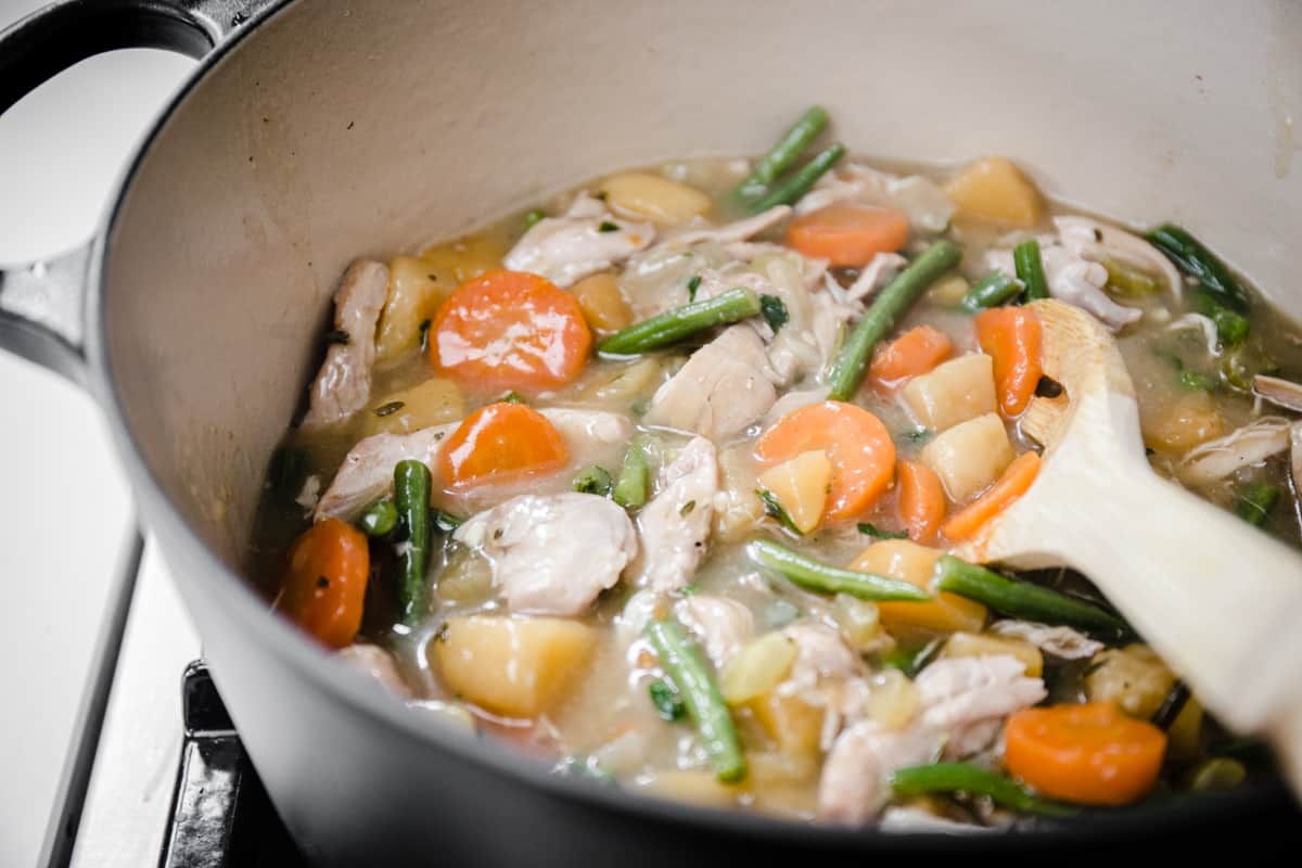 Wooden spoon stirring chicken casserole