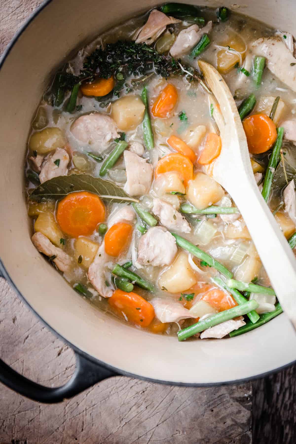 Wooden spoon stirring chicken casserole