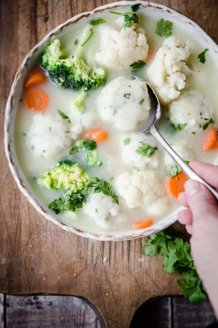 Spoon dipping into bowlful of soup and dumplings