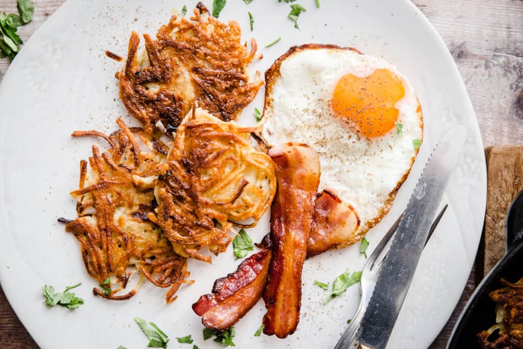 A plate of hash browns, bacon and eggs