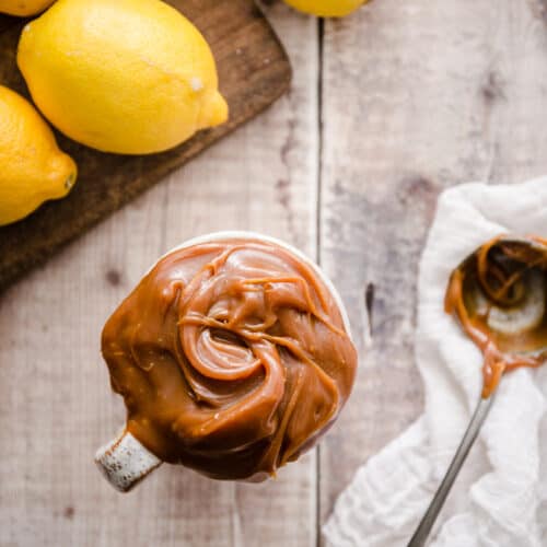 Lemon caramel in a mug with some lemons behind