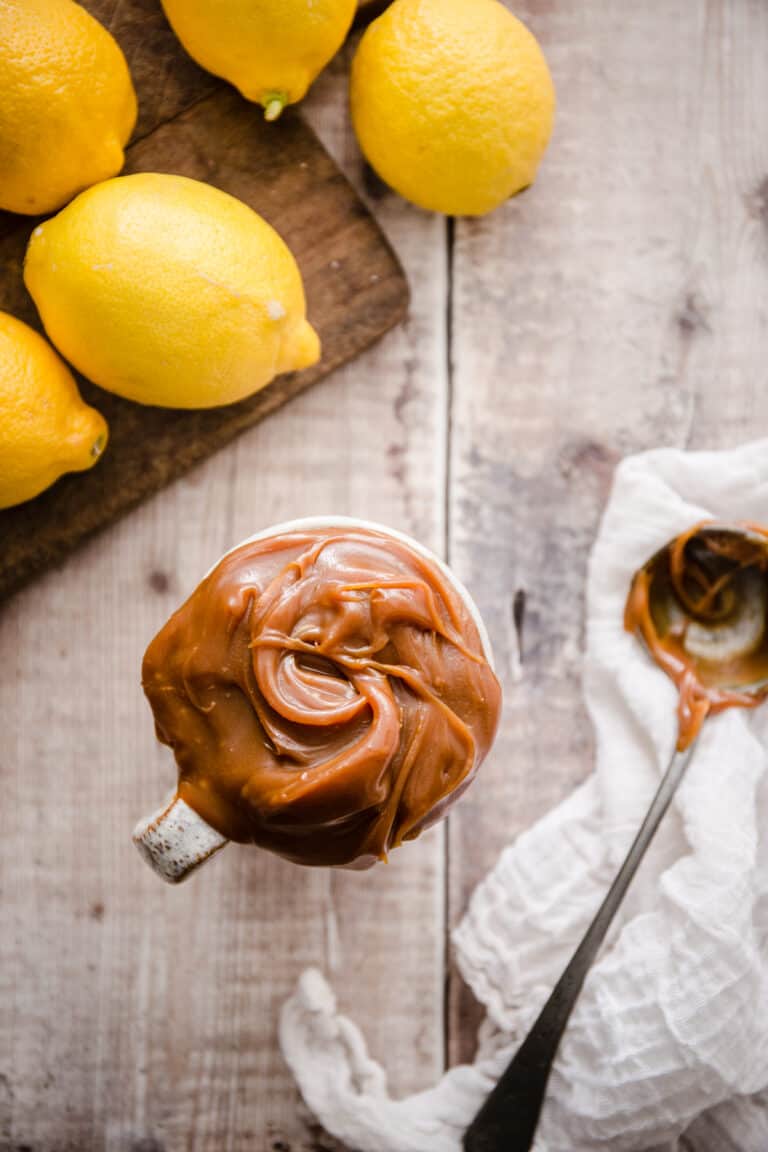 Lemon caramel in a mug with some lemons behind