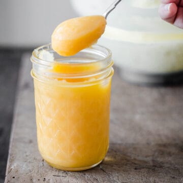 hand holding a spoon dipped into lemon curd