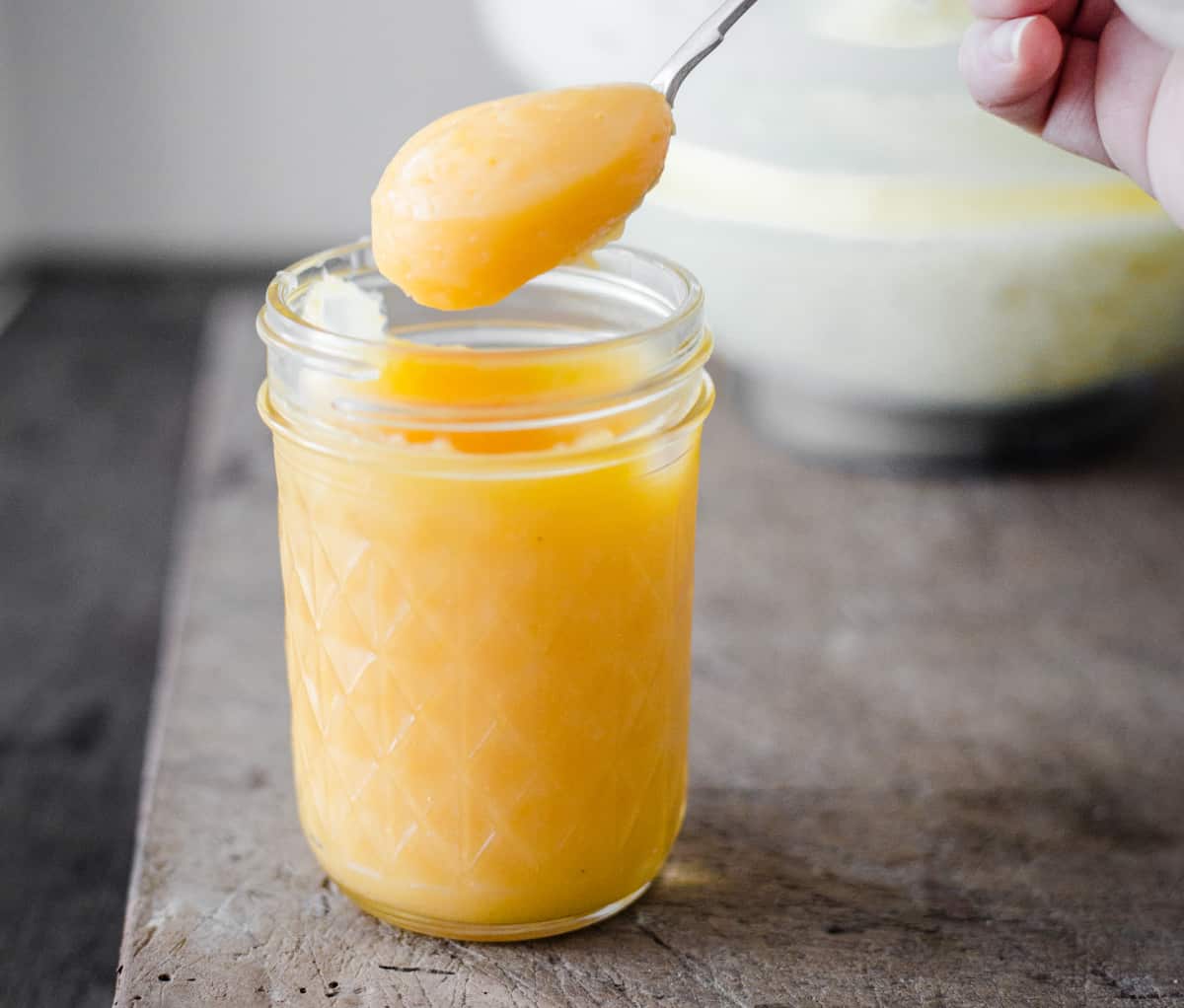 hand holding a spoon dipped into lemon curd