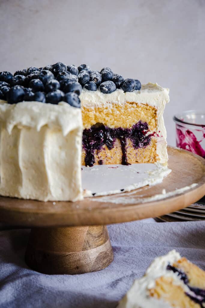 blueberry cake on a wooden stand cut to show inside of cake