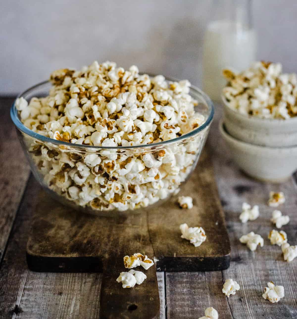 popcorn in a glass bowl on a wooden board
