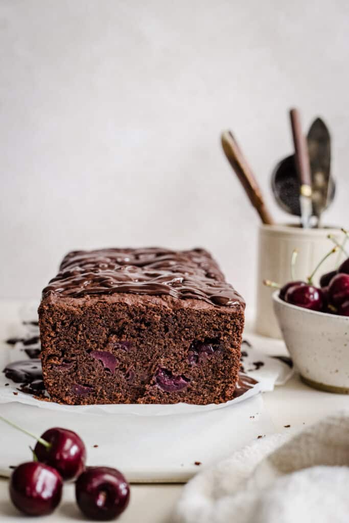chocolate cherry cake on a cake board next to a bowl of cherries